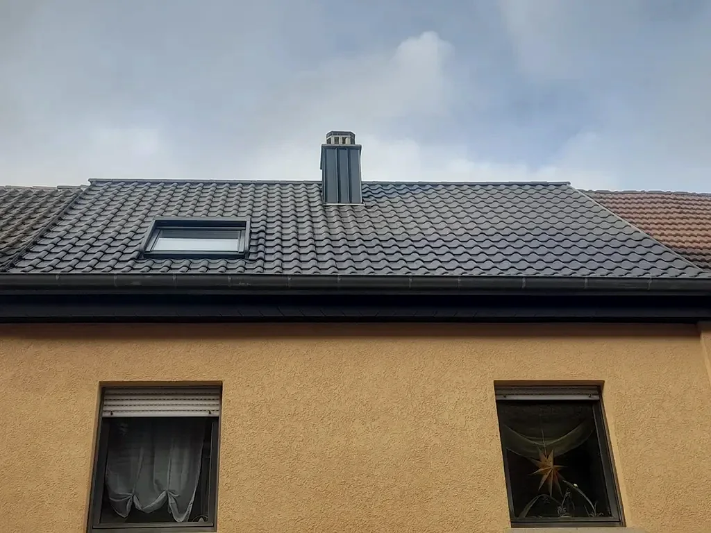 Fertig saniertes Steildach mit Dachfenster und Kamin